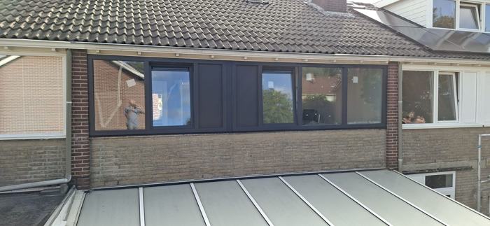 Rij antraciet kozijnen op de verdieping boven een glazen dak