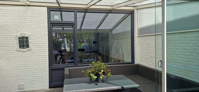 Antraciet kozijn met deur onder een veranda